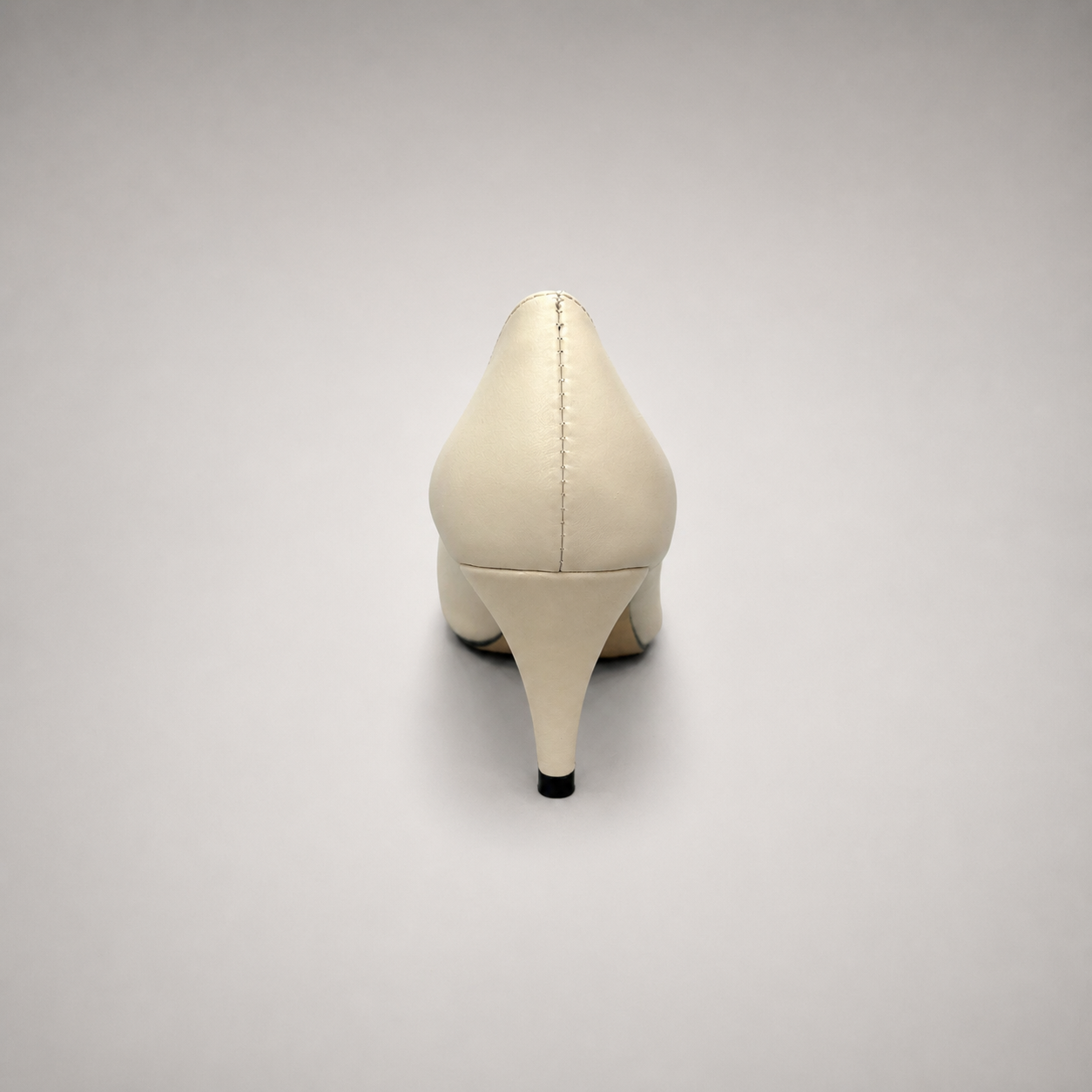 Ivory pump rear view showing a pointed toe and bow-shaped vamp ornament