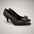 Black pump pair three-quarter view showing a pointed toe and bow-shaped vamp ornament