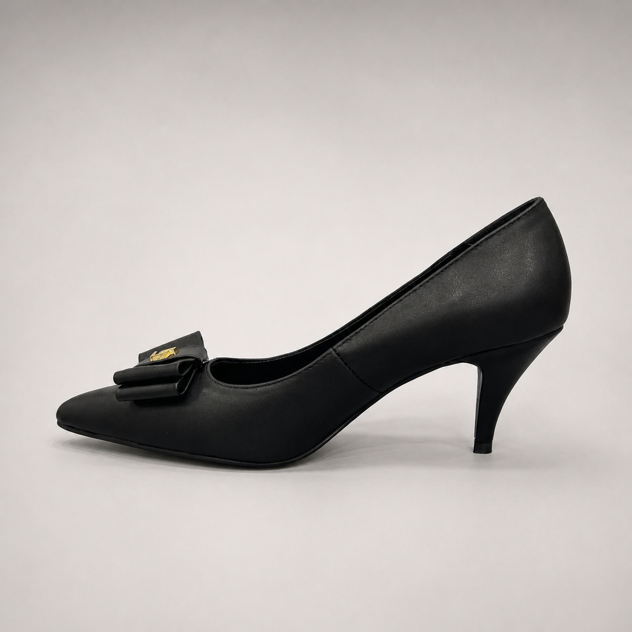 Black pump opposite side profile showing a pointed toe and bow-shaped vamp ornament