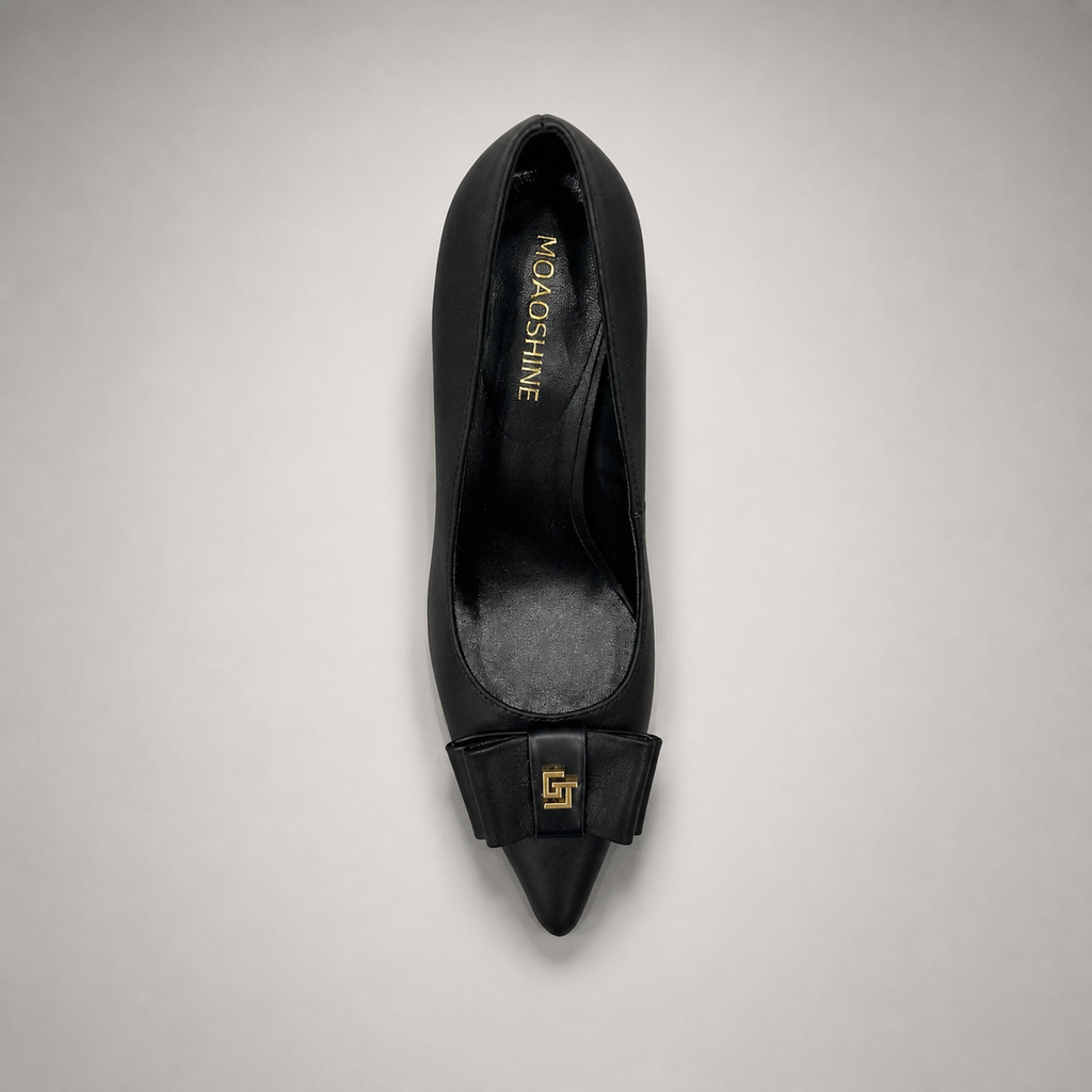 Black pump top view showing a pointed toe and bow-shaped vamp ornament
