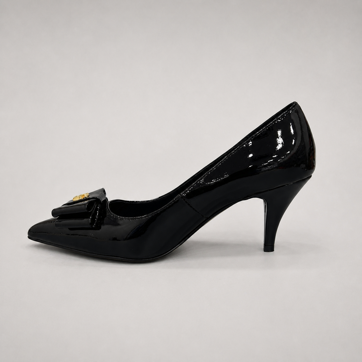Black pump opposite side profile showing a pointed toe and bow-shaped vamp ornament