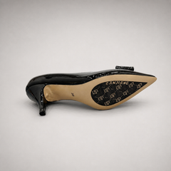 Black pump top view showing a pointed toe and bow-shaped vamp ornament