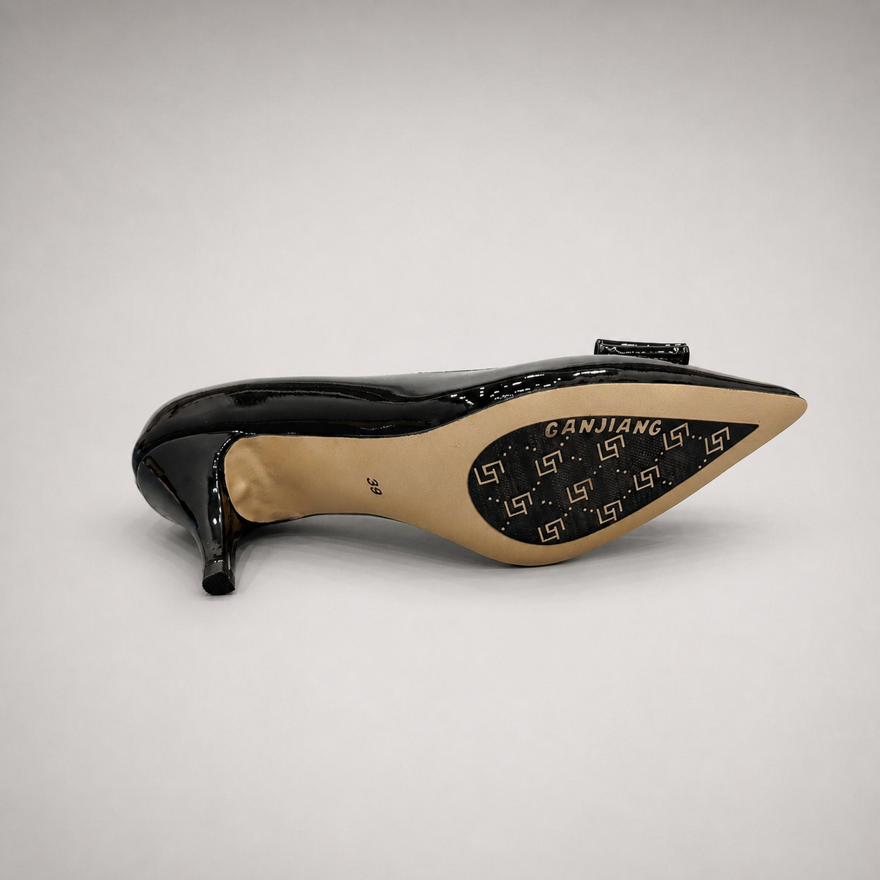 Black pump top view showing a pointed toe and bow-shaped vamp ornament