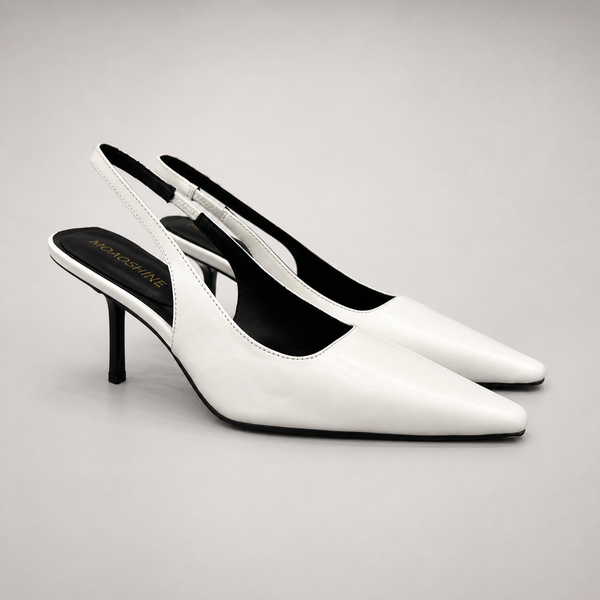 White slingback pump pair three-quarter view showing a pointed toe, angular side cutout, and slingback strap