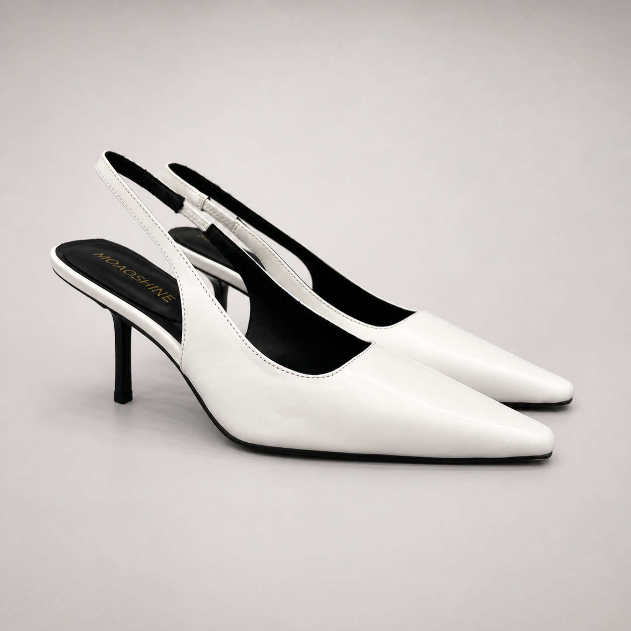 White slingback pump pair three-quarter view showing a pointed toe, angular side cutout, and slingback strap