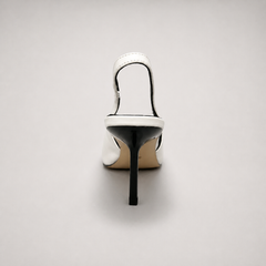 White slingback pump rear view showing a pointed toe, angular side cutout, and slingback strap
