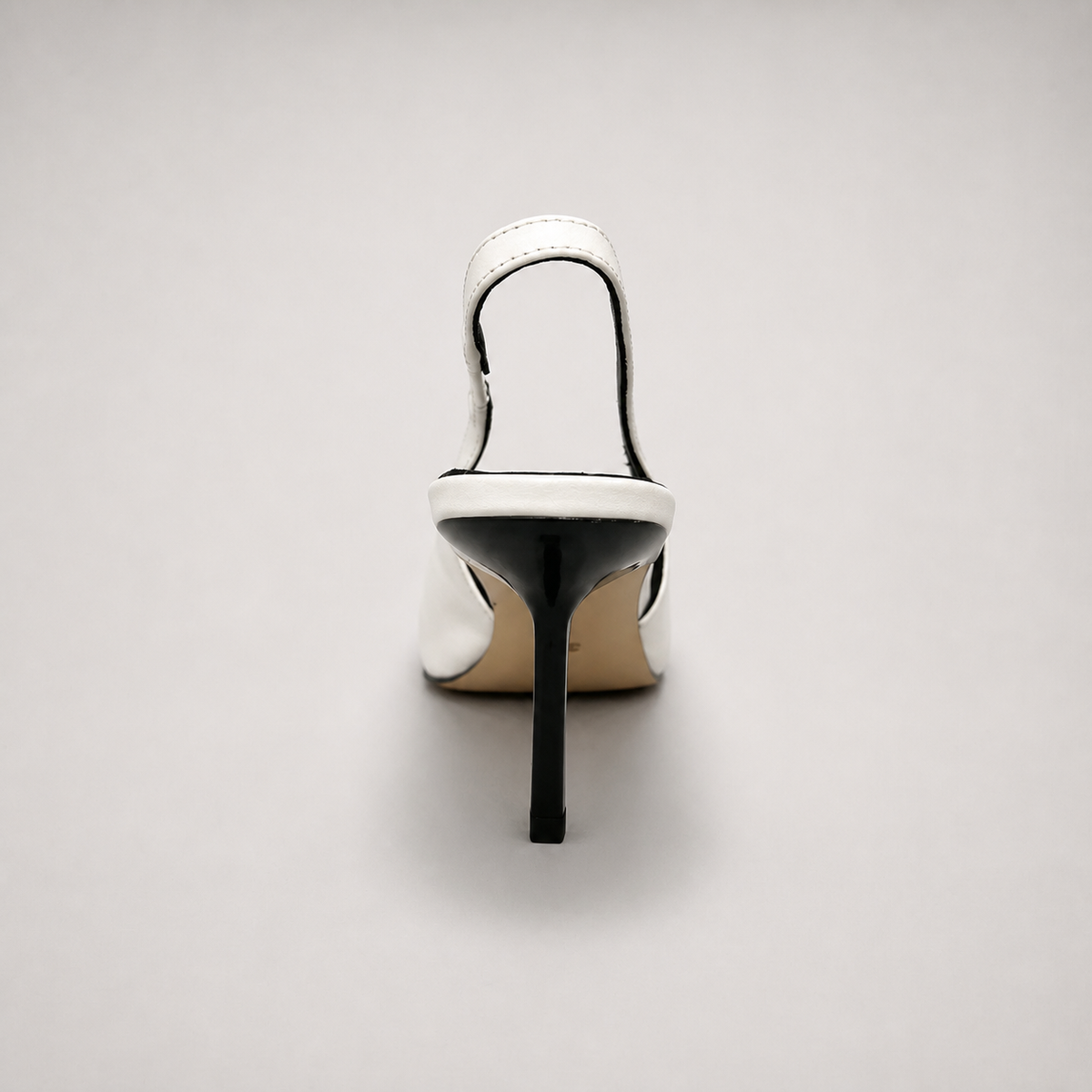 White slingback pump rear view showing a pointed toe, angular side cutout, and slingback strap