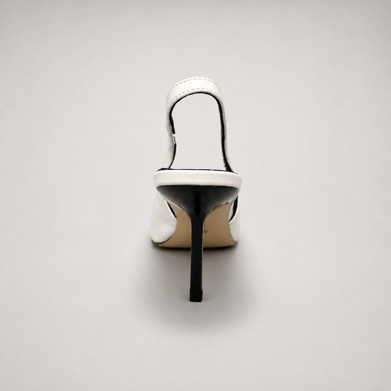 White slingback pump rear view showing a pointed toe, angular side cutout, and slingback strap