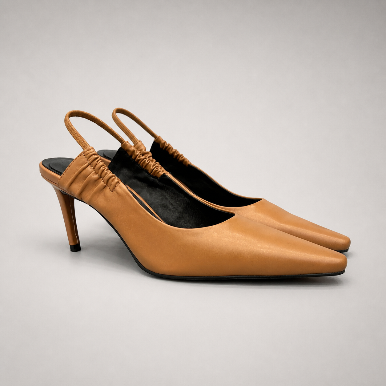 Tan slingback pump pair three-quarter view showing a pointed toe and gathered slingback strap