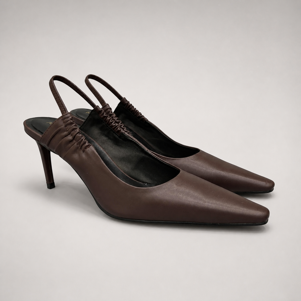 Brown slingback pump pair three-quarter view showing a pointed toe and gathered slingback strap