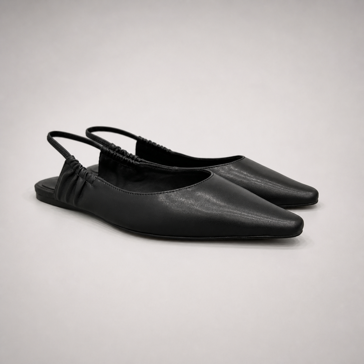 Black slingback flat pair three-quarter view showing a square toe and gathered slingback strap