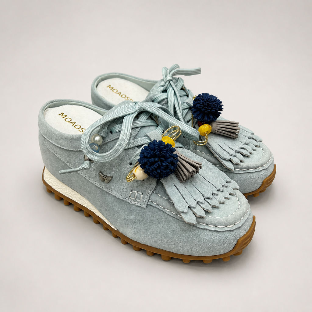 Light Blue moccasin sneaker pair three-quarter view showing fringe and tassel details over the laces
