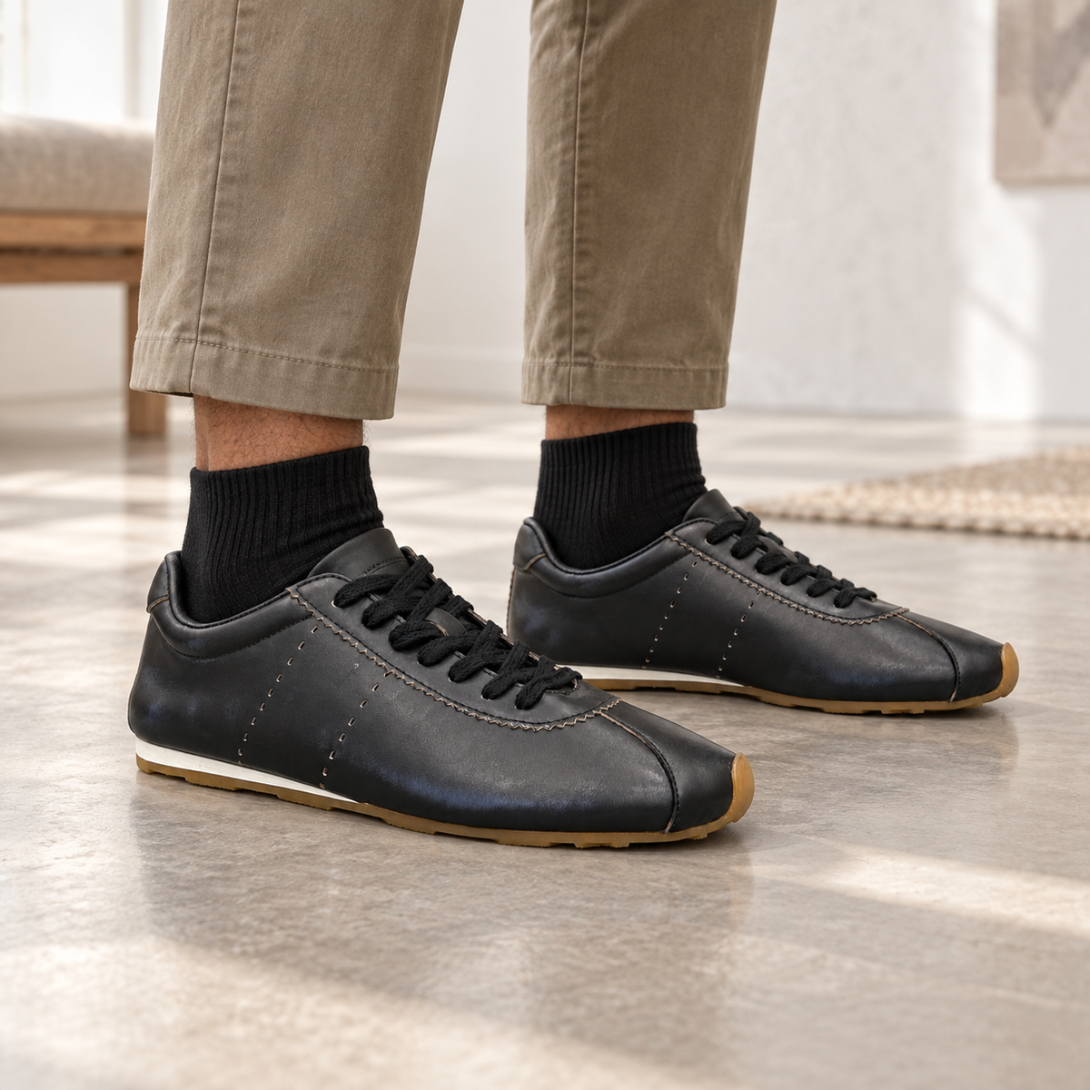 Black smooth oil-waxed leather low-profile sneakers worn with khaki trousers and black ribbed socks