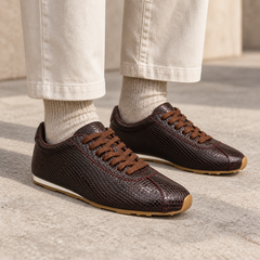 Burgundy snake-embossed lace-up sneakers worn with ecru trousers and oatmeal socks