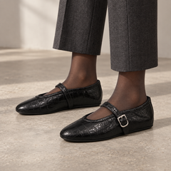 Black croc-embossed oil-waxed leather buckle-strap flats worn with charcoal tailored trousers and sheer hosiery