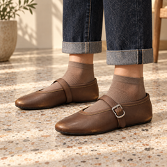 Brown oil-waxed leather buckle-strap flats worn with cuffed indigo jeans and taupe socks