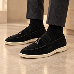Black sheep-suede tassel loafers worn with charcoal trousers and black socks