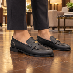 Black emblem loafers worn on feet