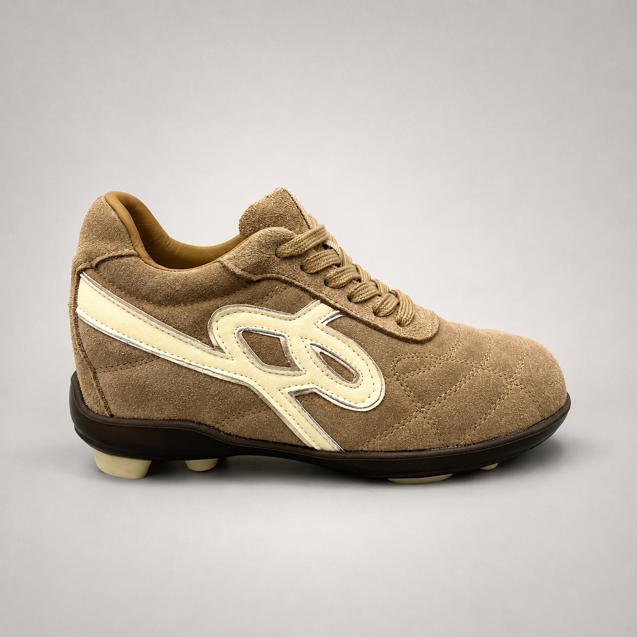 Tan soccer shoe side profile showing a lace-up upper and molded outsole studs
