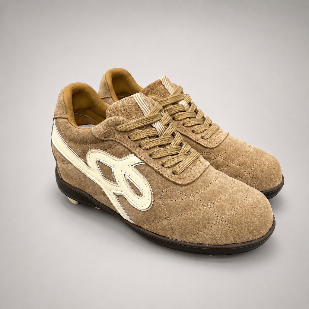 Tan soccer shoe pair three-quarter view showing a lace-up upper and molded outsole studs