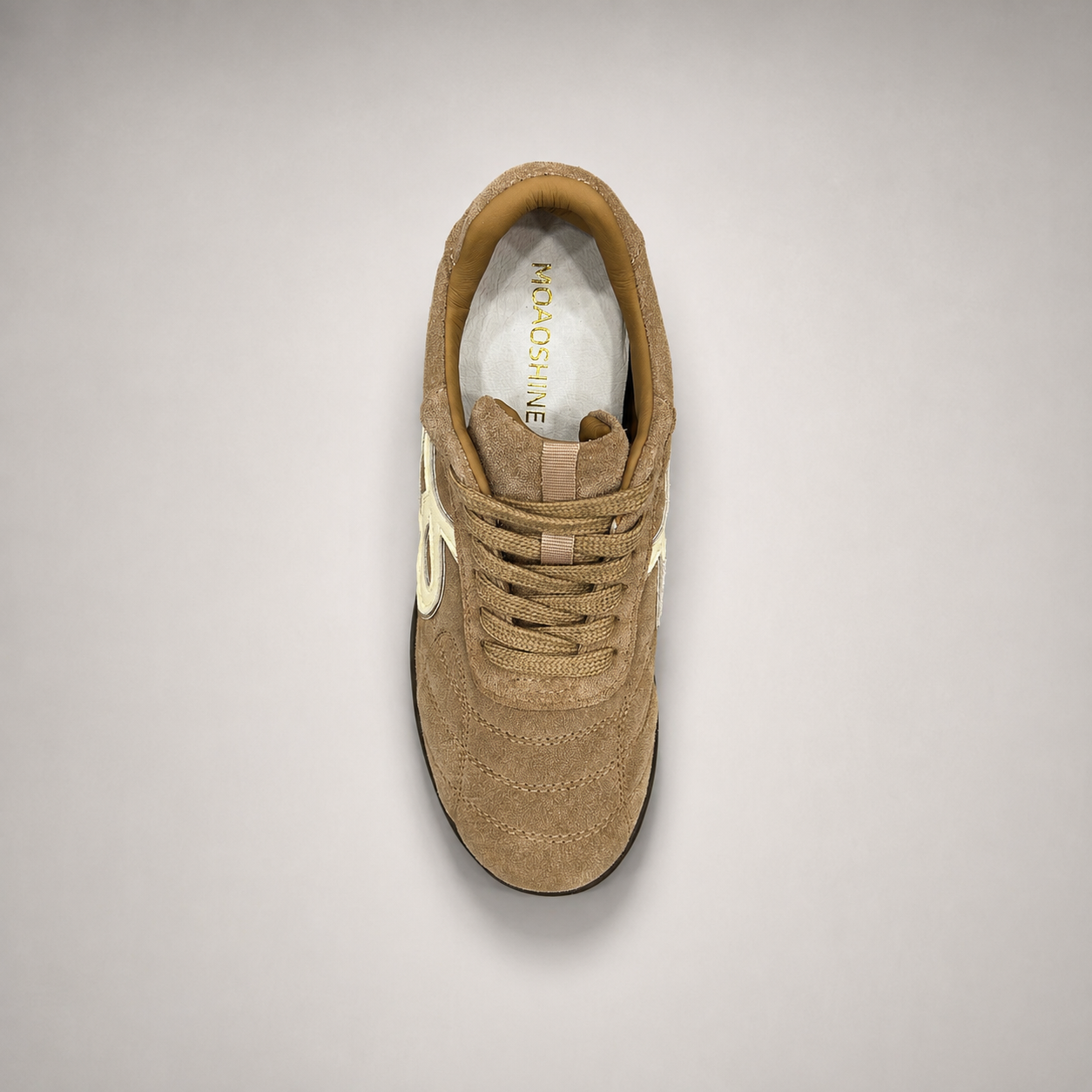 Tan soccer shoe top view showing a lace-up upper and molded outsole studs