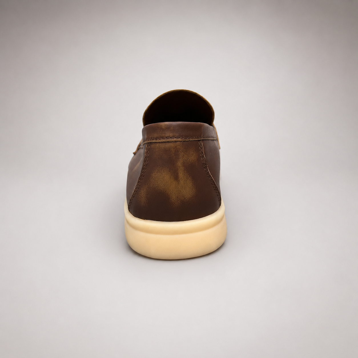 Brown loafer rear view showing a metal accent across the vamp