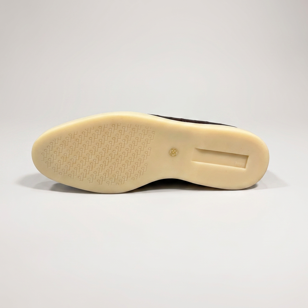 Brown loafer outsole view showing an eel-pattern embossed vamp and tassel detail