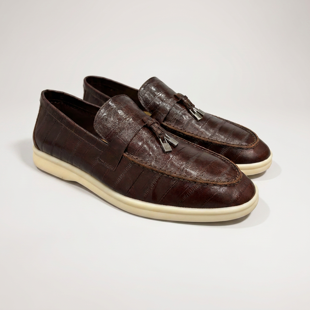 Brown loafer pair three-quarter view showing an eel-pattern embossed vamp and tassel detail