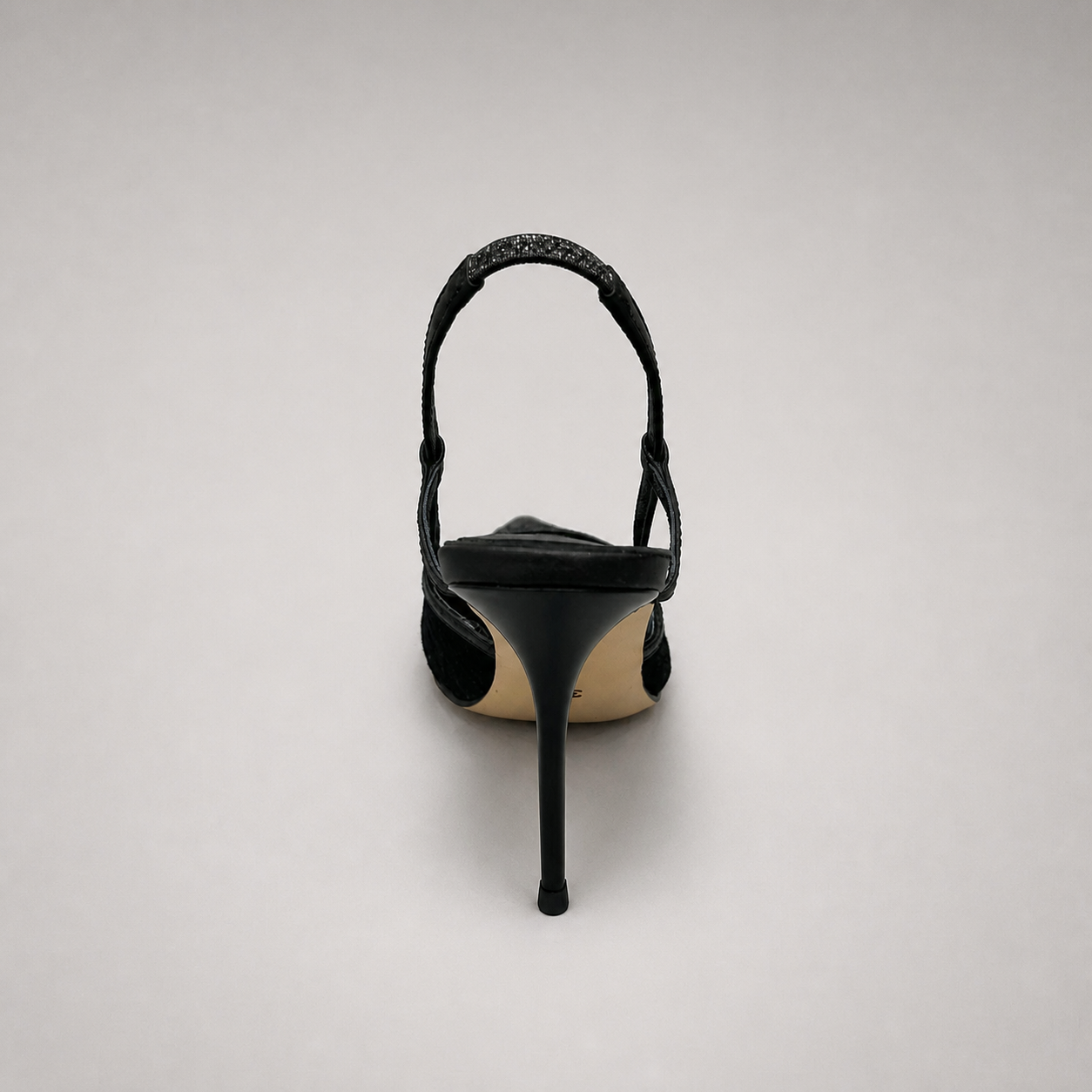 Black slingback pump rear view showing a pointed toe and lace-panel upper