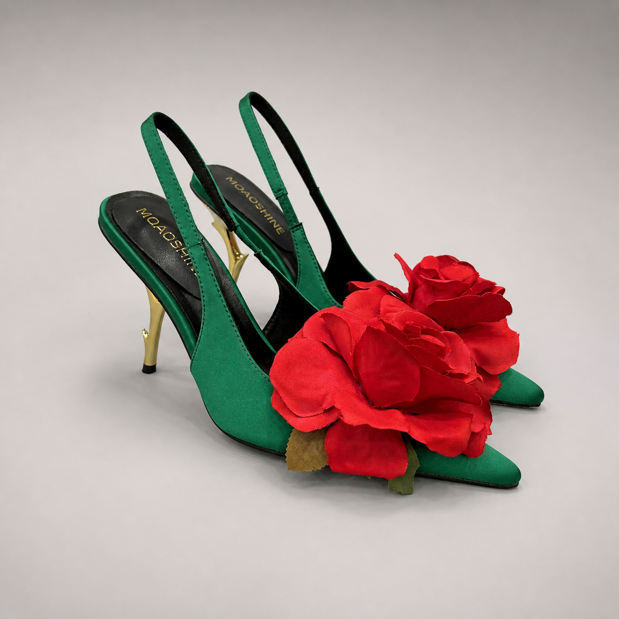 Green slingback pump pair three-quarter view showing a pointed toe and floral appliqué