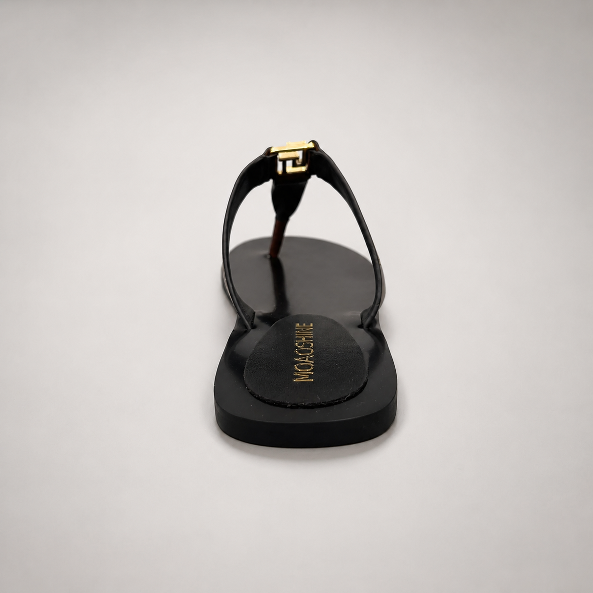 Brown flat sandal rear view showing a flat sole with a toe-loop strap