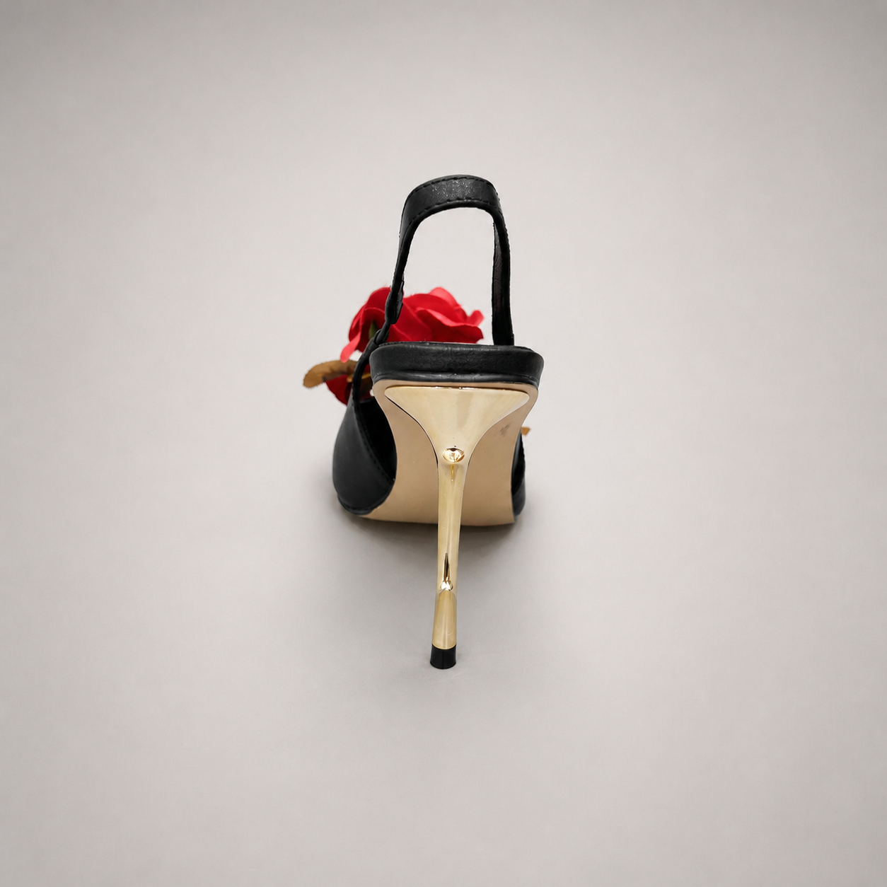 Black slingback pump rear view showing a pointed toe and floral appliqué