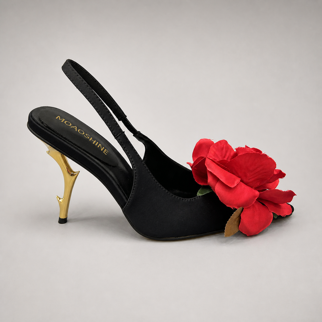 Black slingback pump side profile showing a pointed toe and floral appliqué