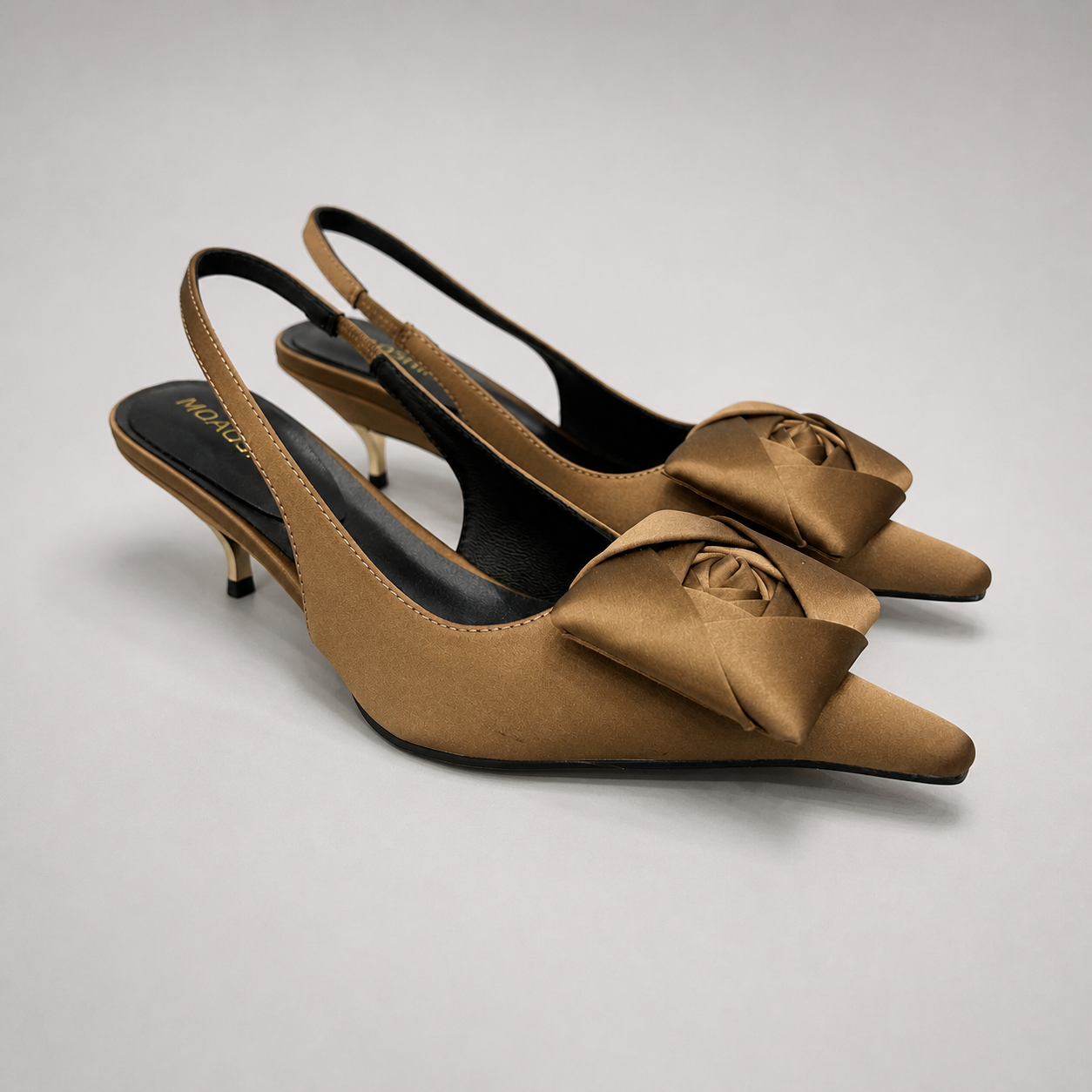 Brown slingback pump pair three-quarter view showing a pointed toe and bow detail