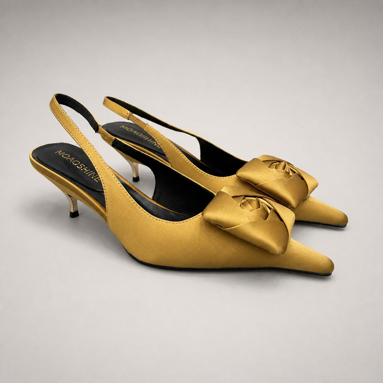 Gold slingback pump pair three-quarter view showing a pointed toe and bow detail