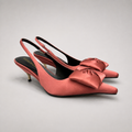 Pink slingback pump pair three-quarter view showing a pointed toe and bow detail
