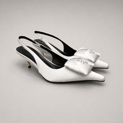 White slingback pump pair three-quarter view showing a pointed toe and bow detail