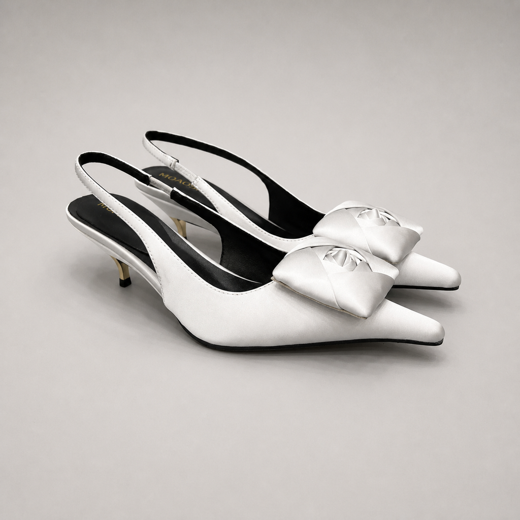 White slingback pump pair three-quarter view showing a pointed toe and bow detail