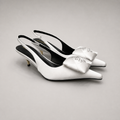 White slingback pump pair three-quarter view showing a pointed toe and bow detail