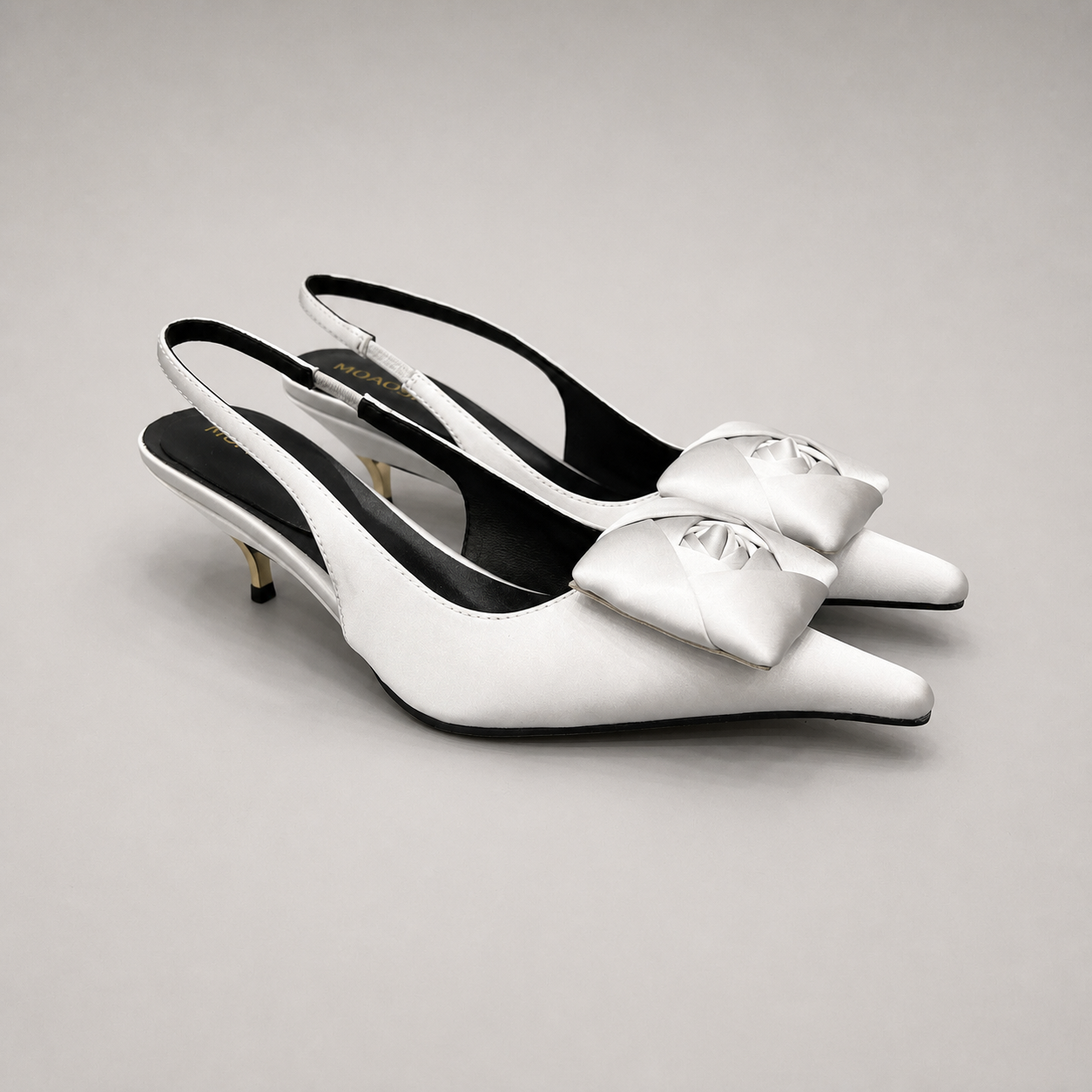 White slingback pump pair three-quarter view showing a pointed toe and bow detail