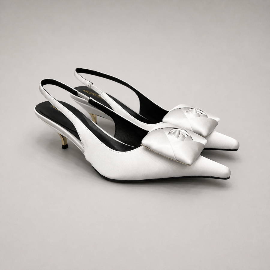 White slingback pump pair three-quarter view showing a pointed toe and bow detail