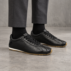 Black croc-embossed oil-waxed leather low-profile sneakers worn with charcoal trousers and black socks