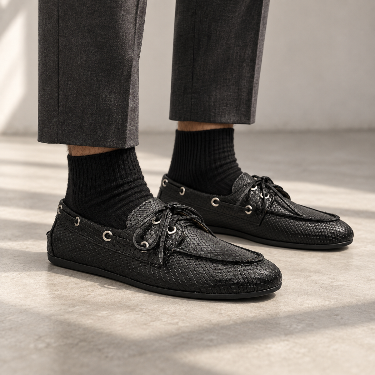 Black snake-embossed oil-waxed leather boat shoes worn with charcoal trousers and black socks