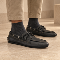 Black top-grain leather boat shoes worn with khaki cropped trousers and charcoal socks