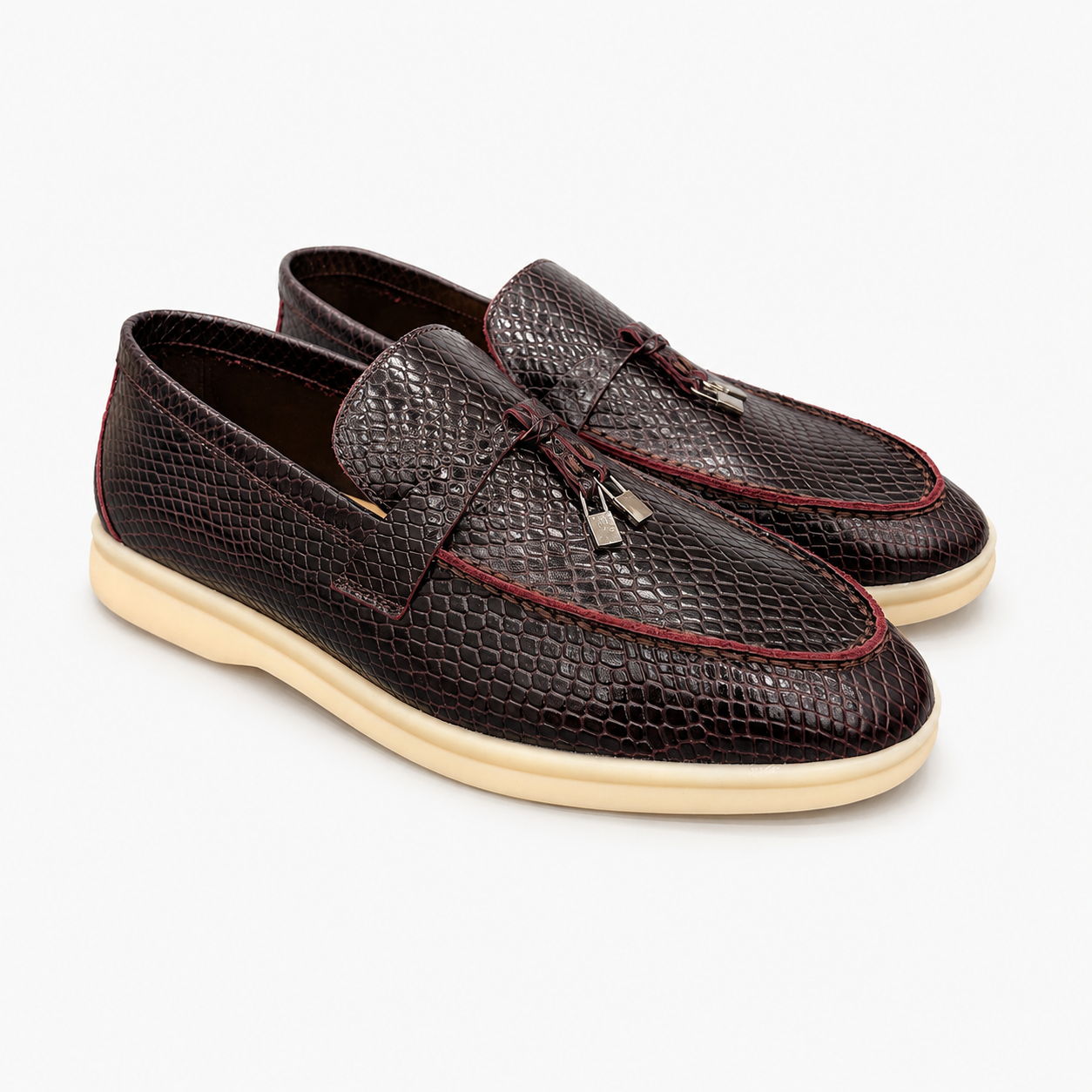 Burgundy loafer pair three-quarter view showing a snakeskin-pattern embossed vamp and tassel detail