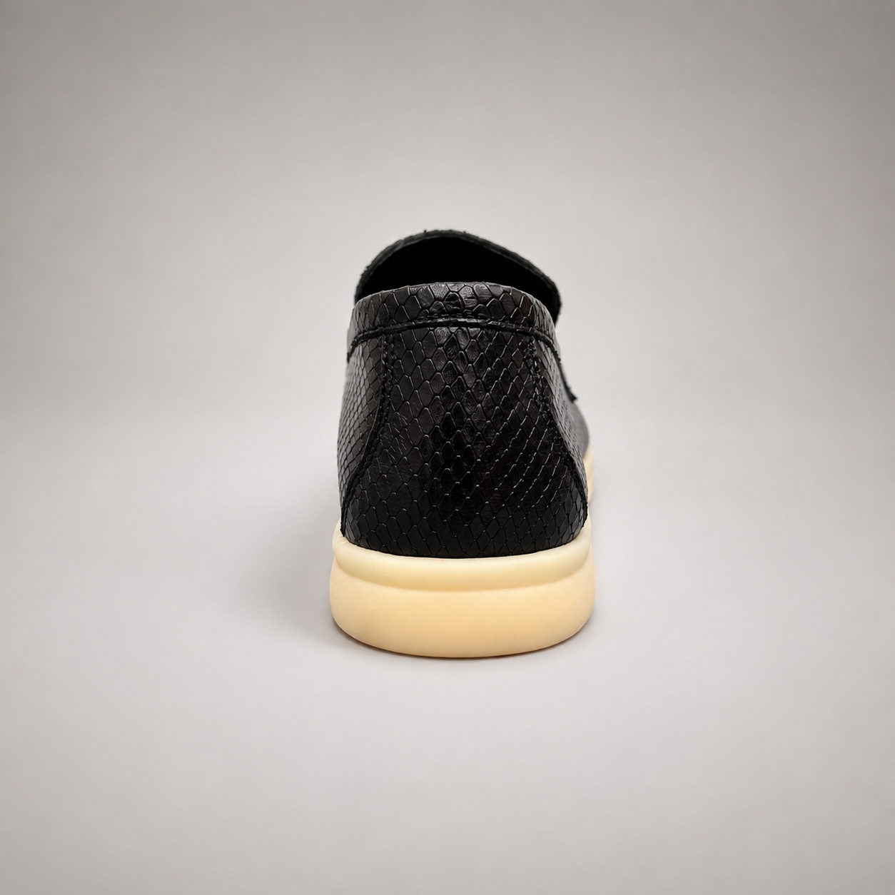 Black loafer rear view showing a snakeskin-pattern embossed vamp and tassel detail