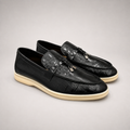 Black loafer pair three-quarter view showing a crocodile-pattern embossed upper and metal accent
