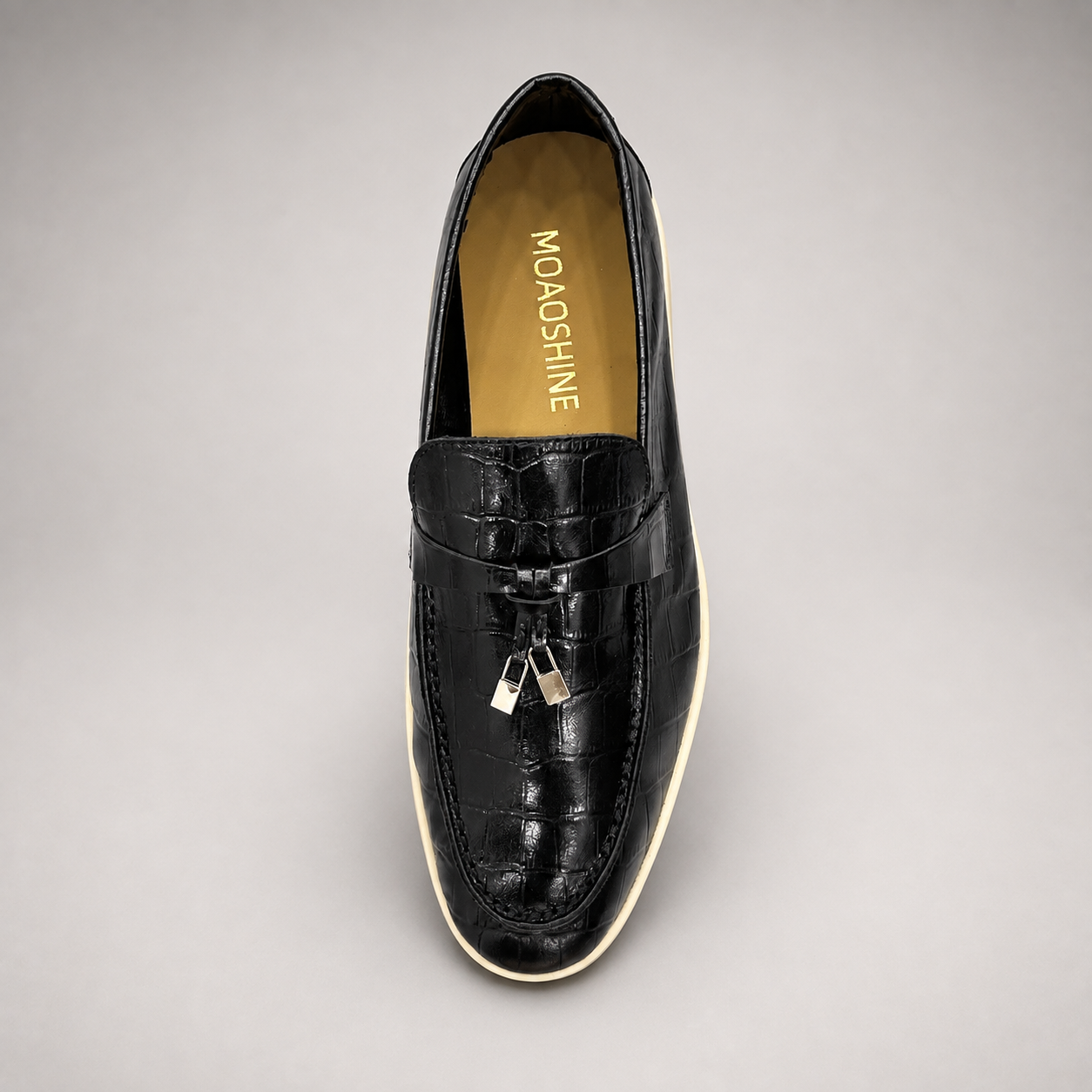 Black loafer top view showing a crocodile-pattern embossed upper and metal accent