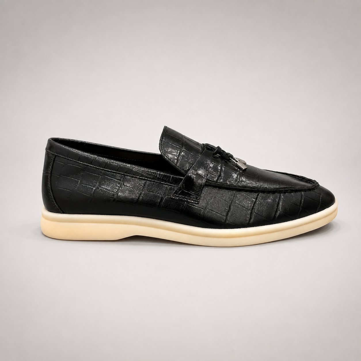 Black loafer side profile showing a crocodile-pattern embossed upper and metal accent