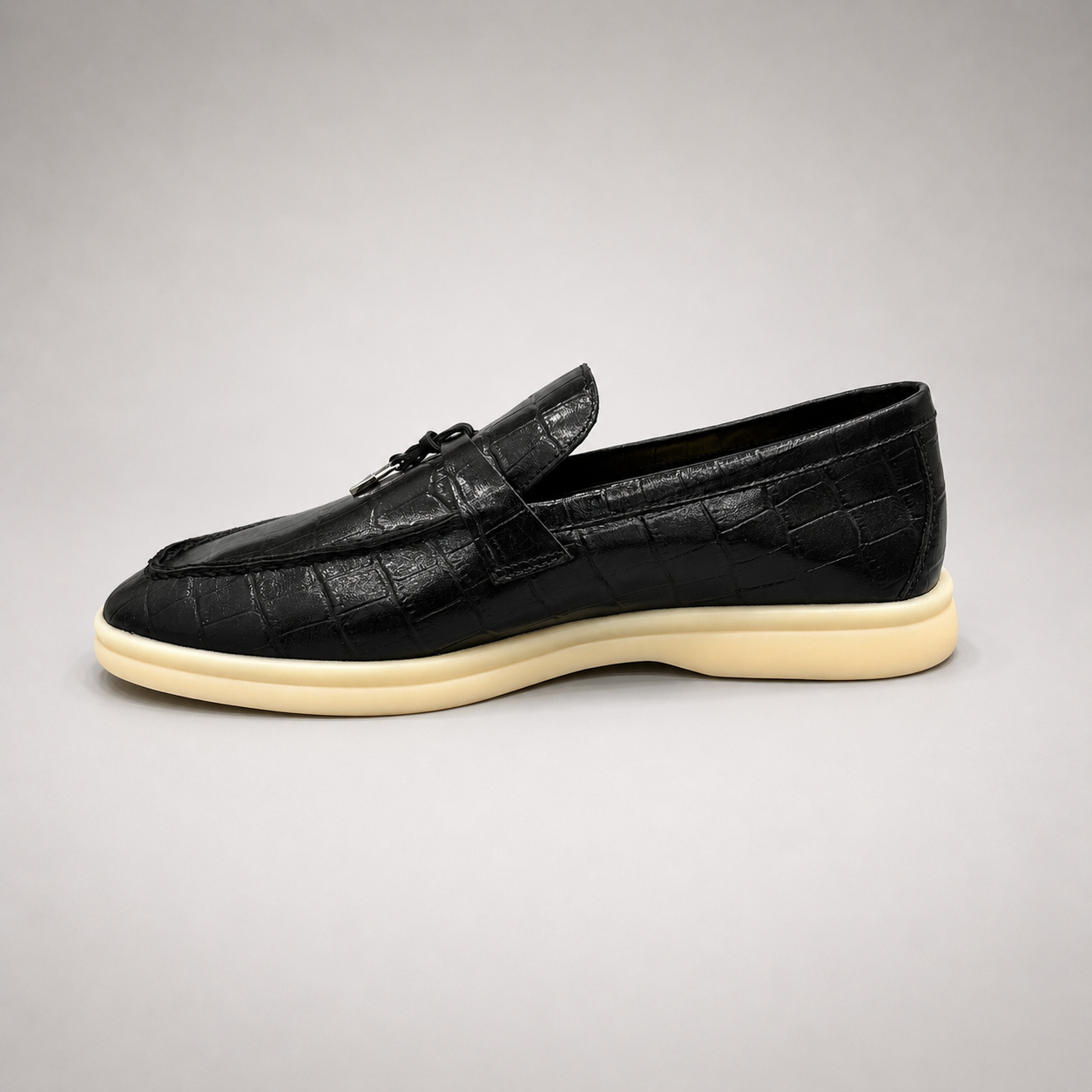 Black loafer opposite side profile showing a crocodile-pattern embossed upper and metal accent